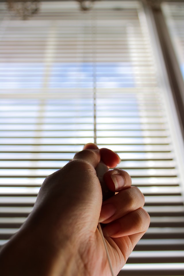 man pulling cord to close roller blind